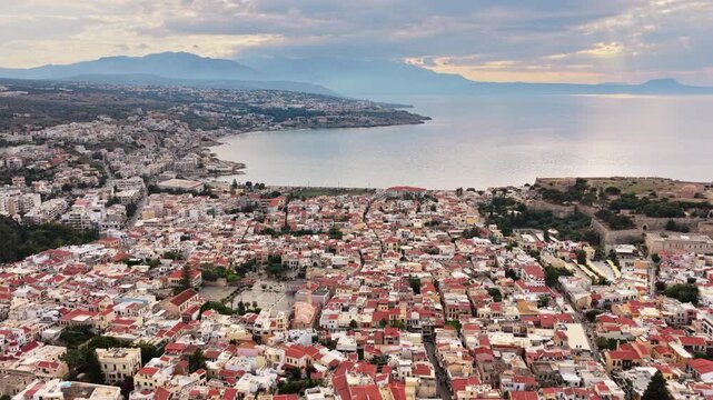 Aerial drone view of the dense red-roofed old town and the Fortezza on the coast, Rethymno, Greece