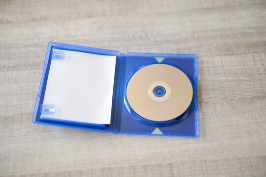BRECHT, BELGIUM &ndash; July 10, 2026: Close-up of an open PlayStation 5 game case with a physical game disc lying inside on a wooden table, highlighting physical gaming media for editorial use.