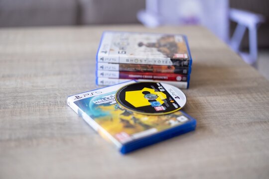 BRECHT, BELGIUM &ndash; July 10, 2026: Close-up of several PlayStation 5 game cases stacked beside a closed Blu-ray game case for editorial use.