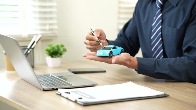Insurance agent presenting a car model over policy documents, symbolizing auto insurance, vehicle protection, and financial security.