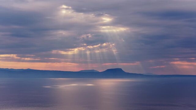 Aerial drone view of dramatic sun rays breaking through clouds over the calm sea, Crete, Greece