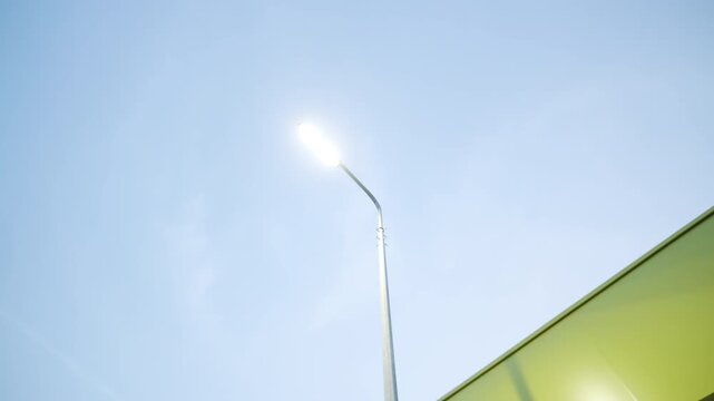 Tall street lantern illuminates building with contrasting panel details. Bright electric light provides visibility around commercial site