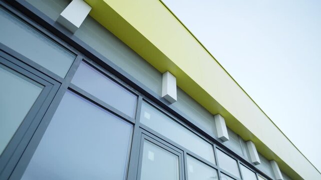 Building facade features large windows and contrasting panels. Lines along with reflections suggest quality construction of facility