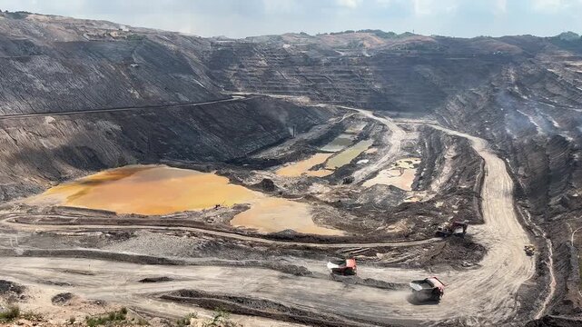 Haul Trucks Transporting Material Along Dirt Road in Open Pit Mine