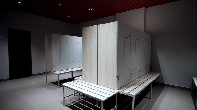 Lockable lockers with two-tone light wood and grey panels stand in advanced facility. Wooden benches positioned near storage clusters