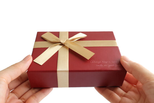 Hands Holding a Red Gift Box with Gold Ribbon Isolated on White