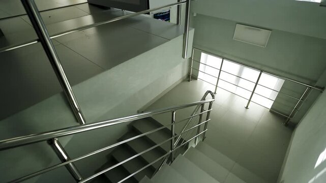 Concrete staircase features stainless steel railings and tiled floors. Clean design creates bright spacious environment inside building