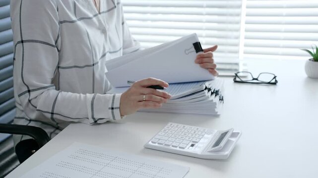 Financial professional carefully reviewing business documents with a magnifying glass while calculating numerical data, demonstrating diligent tax preparation and detailed audit analysis