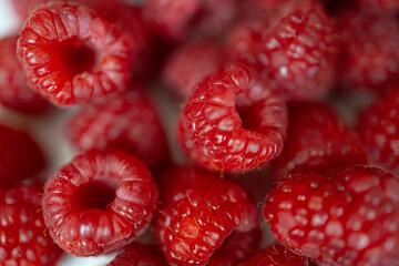 Detailed macro view of ripe red raspberries with glossy texture and natural light reflections, emphasizing freshness and vibrant color. © Е С