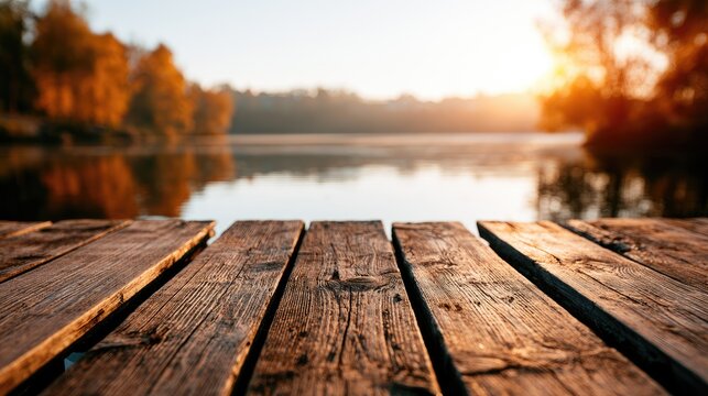Sunlit wooden dock by tranquil lake with autumn foliage