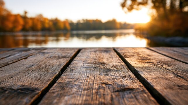 Rustic wooden dock with tranquil lake and golden autumn trees at sunset