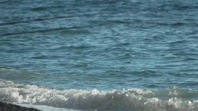 Fishing, ocean, beach rods set up waiting for a catch on a sunny day with small turquoise waves.