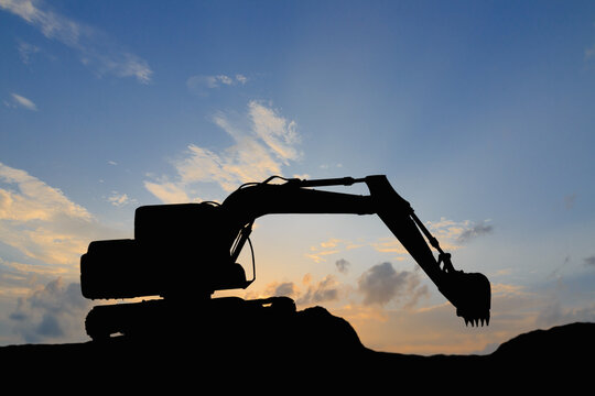 Crawler excavators silhouette are digging the soil in the construction site on   sunset sky background
