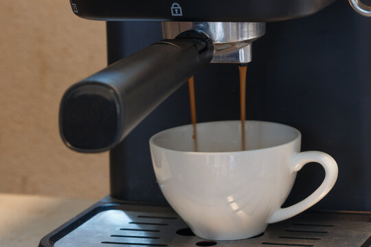 Coffee machine pouring espresso coffee in a white mug