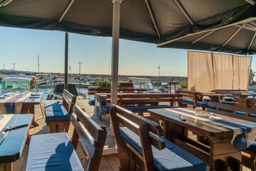 Fototapeta premium Outdoor restaurant terrace overlooking marina with boats on sunny summer day