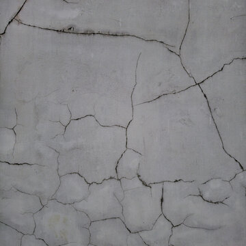 Old light wall with large cracks. Concrete and plaster texture background.