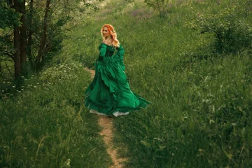 Happy fantasy woman medieval queen noble lady walking in summer nature footpath. elf redhead girl princess running at forest path green grass trees. fairy tale noble lady in long dress looking back © kharchenkoirina