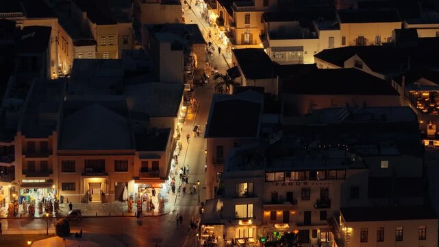 Aerial drone view of the illuminated pedestrian streets of the old town at night, people strolling among red-roofed houses, Rethymno, Greece