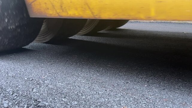 Road Roller Compacting Asphalt: A close-up shot of a road roller's heavy wheels compressing fresh asphalt on a construction site, smoothing the surface for a new road.