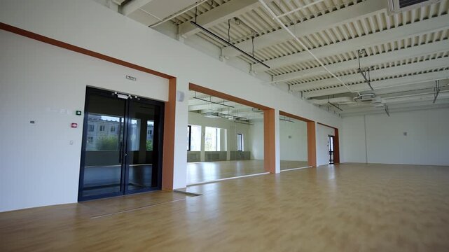 Spacious quiet athletic facility shows modern design. Daylight brightens wall with windows. Hall holds anticipation for athletes arrival