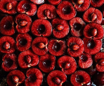Fresh ripe sweet cherry halves arranged as a full frame background. Organic summer berries with juicy red flesh. Top view food texture.