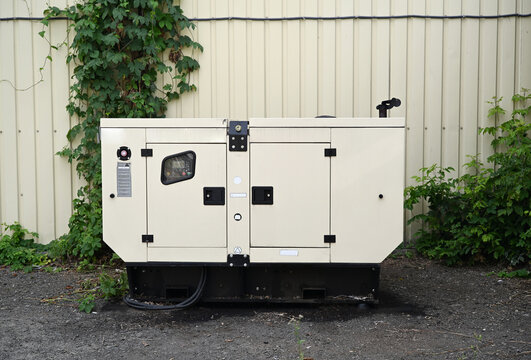 Industrial standby generator unit installed outdoors beside a building for backup electrical power.
