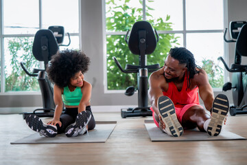 Fototapeta premium African American father daughter stretching legs yoga mat gym. Concept of family fitness, healthy active lifestyle, flexibility training and strong family bonding.