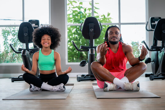 African American father daughter meditating yoga mat gym. Concept of family fitness, healthy active lifestyle, mindfulness training and strong family bonding.