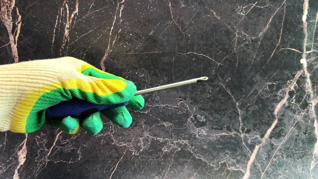 Close-up of a gloved hand holding a Phillips screwdriver on a dark background. The concept of repair, twisting, handyman, construction. High quality 4k footage 