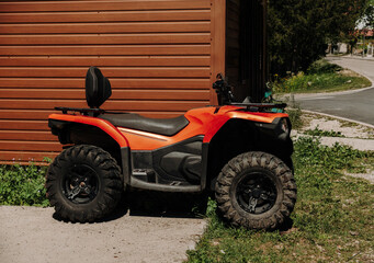 Orange all-terrain vehicle parked beside a wooden building in Montenegro. Off-road transport commonly used in mountain and rural areas. © Ekaterina