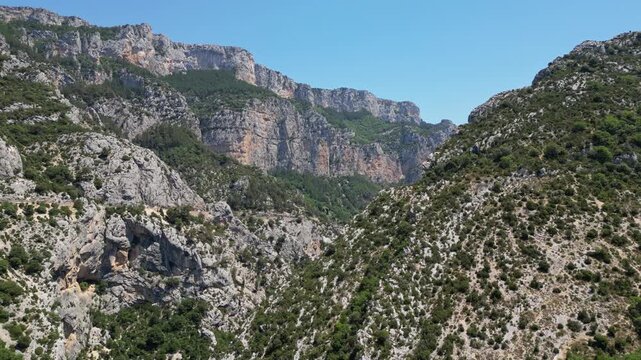 Aerial top-down view of the spectacular Verdon Gorge canyon with winding mountain road, dramatic limestone cliffs and emerald river, Provence, France