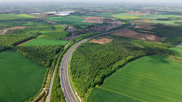Aerial landscape footage of a major motorway in the UK winding its way through countryside into the distance with traffic and copy space