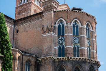Obraz premium Historic Gothic Brick Cathedral with Ornate Windows and Medieval Architecture in Italy