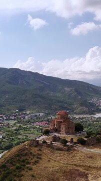 Jvari monastery aerial rotating view with mtskheta town and kura river in the background, a unesco world heritage site in georgia showing its ancient religious architecture