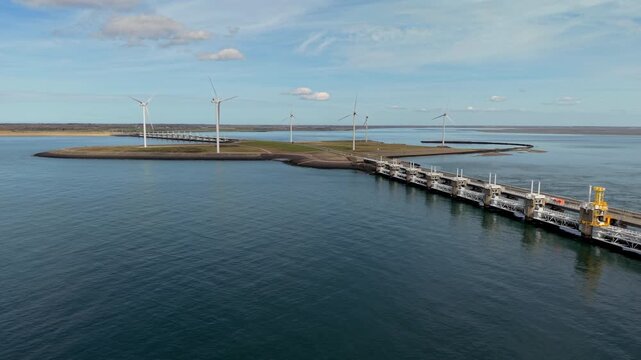 Aerial wide angle panoramic view of the massive Oosterscheldekering storm surge barrier bridge and modern offshore wind turbines inside the delta works flood protection system