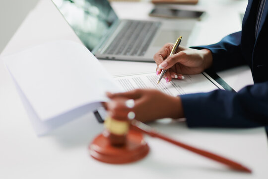 Lawyer reviewing legal documents and signing a contract at a desk, with a gavel nearby, representing justice, legislation, and resolving important business matters
