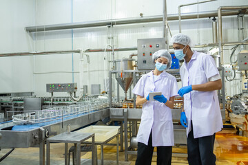 Two food industry professionals engaging in a conversation about quality assurance processes within a production environment © Surachai