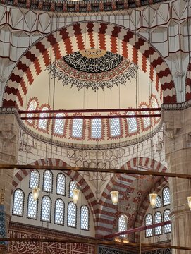 ​Low angle interior view of the magnificent Selimiye Mosque in Edirne, Turkey, showcasing the ornate marble minbar (pulpit), grand arches with red and white voussoirs, Islamic calligraphy