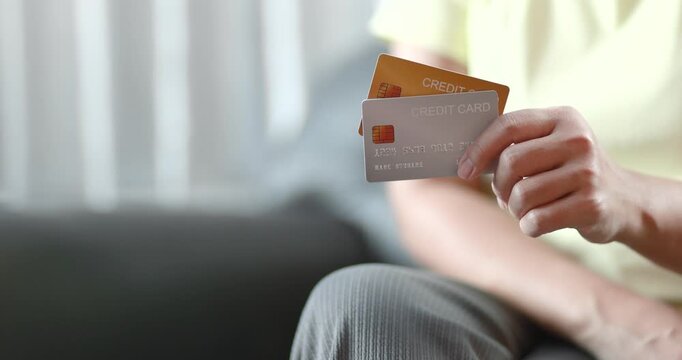 Woman holding two credit cards for comparison or online payment. Personal finance, e-commerce, fintech, cashless transaction, and copy space, close-up