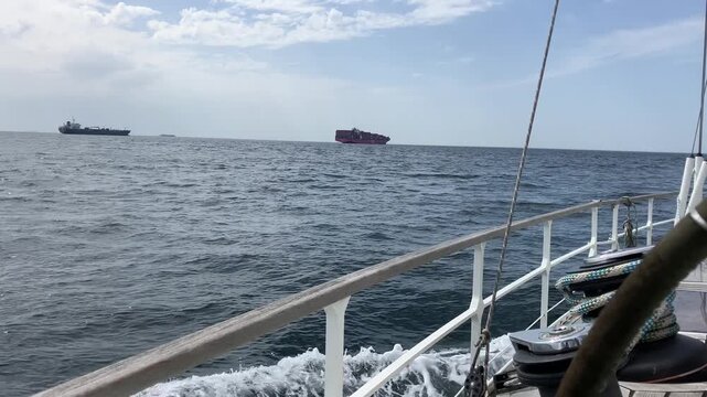 Rolling Sailboat View With Cargo Ships Offshore