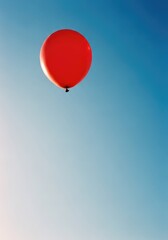 Fototapeta premium A vibrant red balloon floats gracefully against a clear blue sky, captured on analog film with soft grain and natural sunlight effects, altitude, cinematic, high