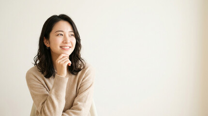 Fototapeta premium 斜め上を見上げ、微笑みながら考え事をする若くて美しい女性のイメージ画像