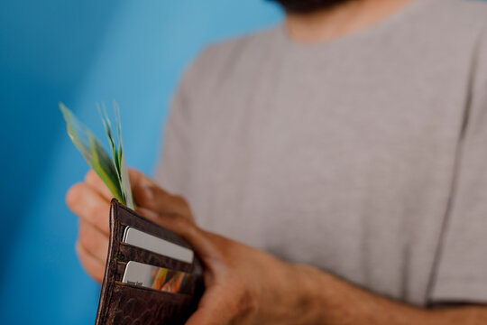 Close-up of a person holding a brown leather wallet full of cash and credit cards.