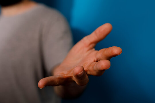 An open hand reaching forward against a blue background, symbolizing offering help, support or conne