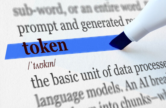 Token word highlighted in blue marker in dictionary with AI language model definition, artificial intelligence terminology concept