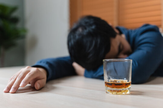drunk man fall asleep on the table with whiskey glass