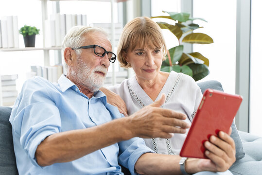 relaxed mature couple using touchpad computer shopping online in the living room.