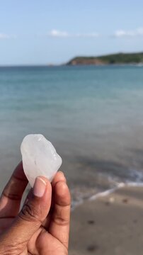 Hand Holding Smooth White Sea Stone Found on Tropical Beach