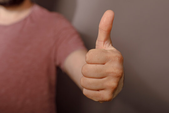 Close up of a person giving a thumbs up gesture, conveying approval and positivity.