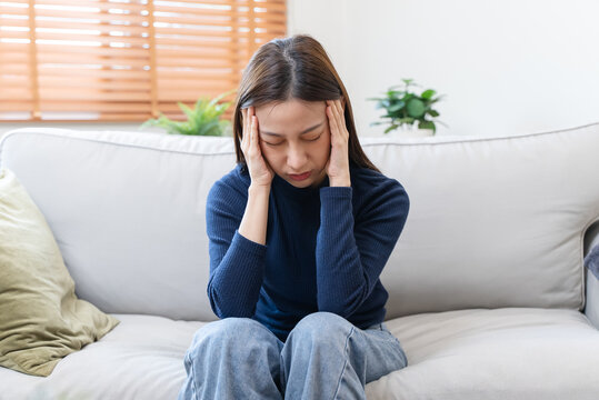 Young woman feeling headache sitting on sofa.